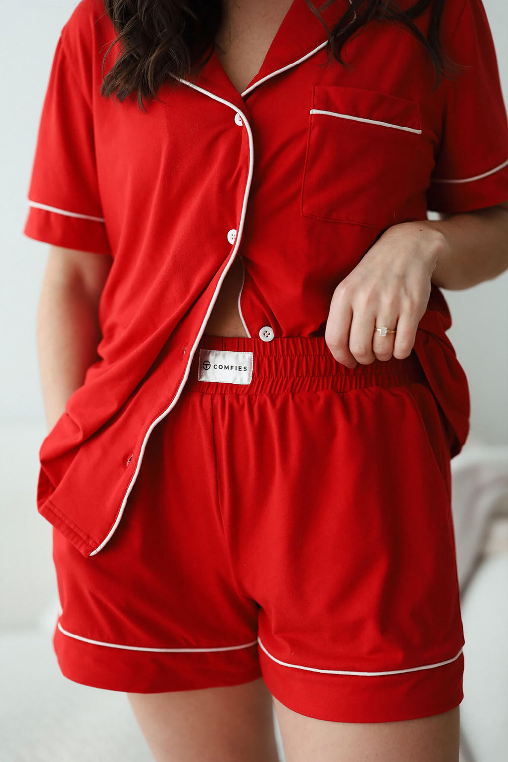 Close-up of red short sleeve pajama set with button-up top, white piping, and elastic waistband shorts.