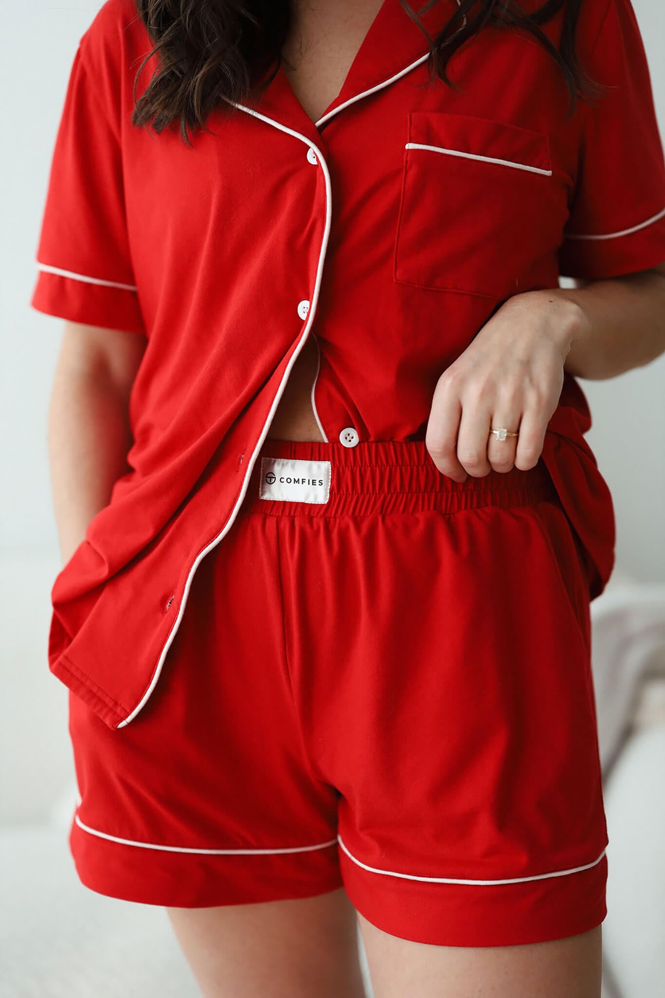 Close-up of red short sleeve pajama set with button-up top, white piping, and elastic waistband shorts.